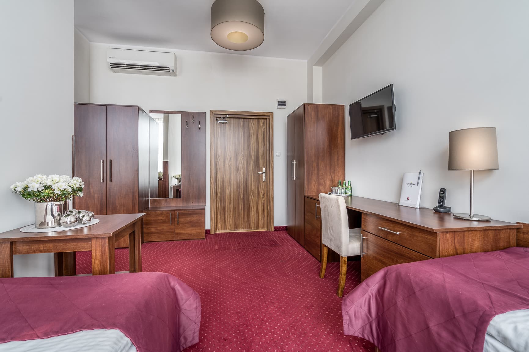 Pokój hotelowy z szafą, biurkiem i telewizorem
