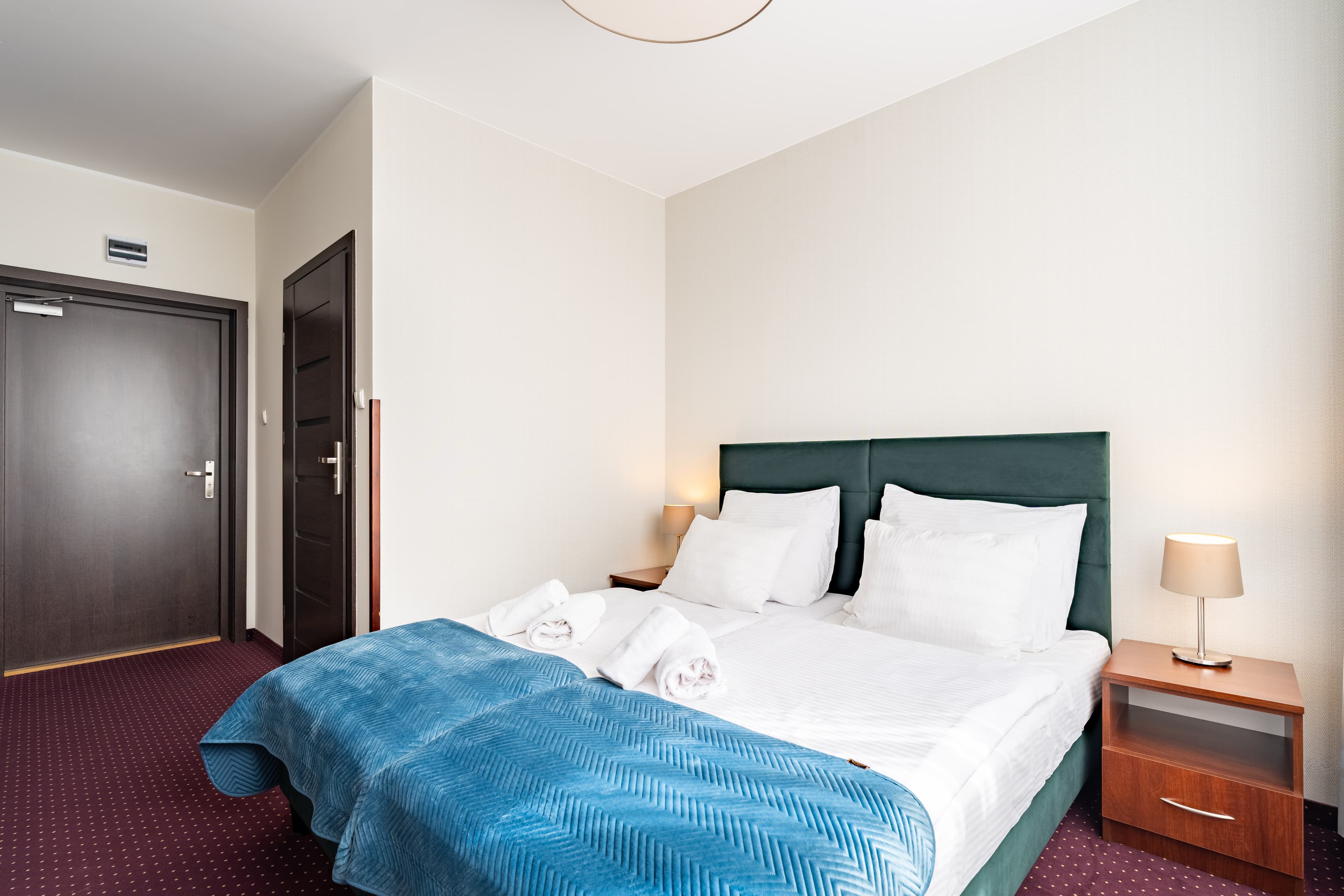 Wygodne łóżko z białą pościelą w pokoju hotelowym